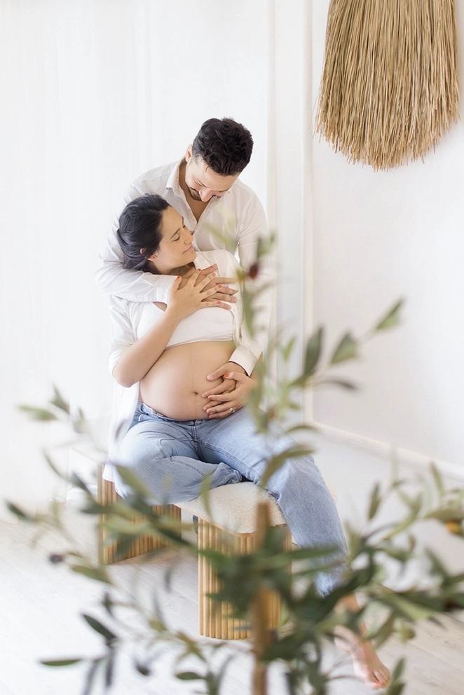 Photo d'un futur parents qui se serre fortement en regardant le ventre de la future maman lors d'une séance photo avec Tiana Photographe Toulouse