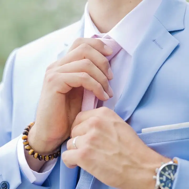 Photo des mains du marié qui est en train de faire son cravate