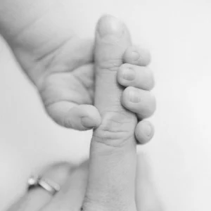 Photo d'une main d'un bébé accroché au doigt de sa maman lors d'une séance photo avec Tiana Photographe Toulouse