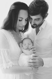 Photo d'un couple avec son bébé dans les bras côte à côte lors d'une séance photo avec Tiana Photographe naissance Toulouse