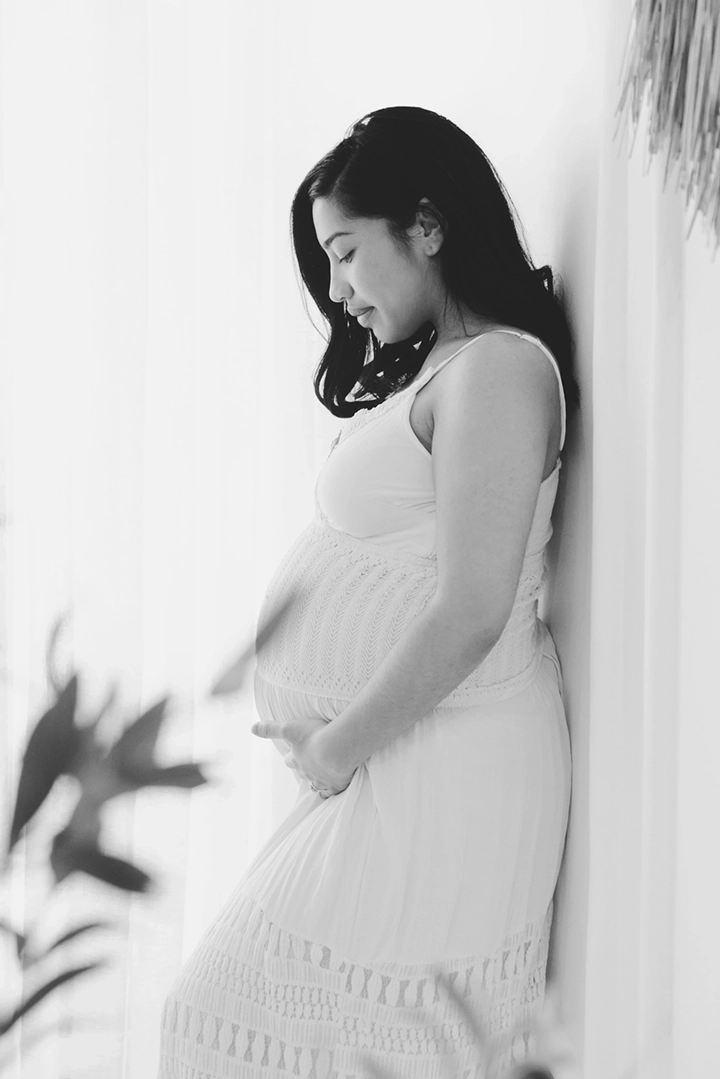 Photo de grossesse qui regarde son ventre avec amour dans le studio de Tiana Photographe Toulouse