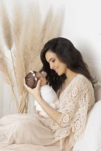 Photo d'une maman qui tient son bébé dans les bras en le regardant délicatement. Photo prise par une photographe naissance à Toulouse