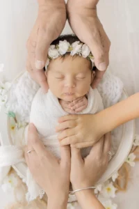 Photo d'un bébé entouré des mains de sa famille lors d'une séance photo avec Tiana Photographe Toulouse