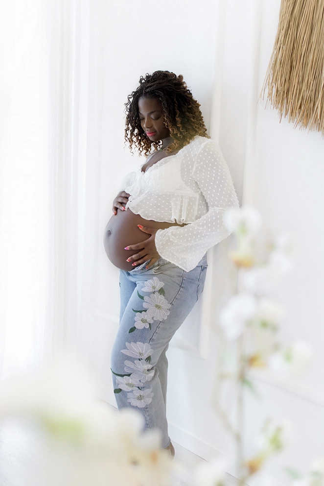 Un futur maman africaine regardant son ventre tendrement lors d'une séance photo au studio de Tiana Photographe Toulouse