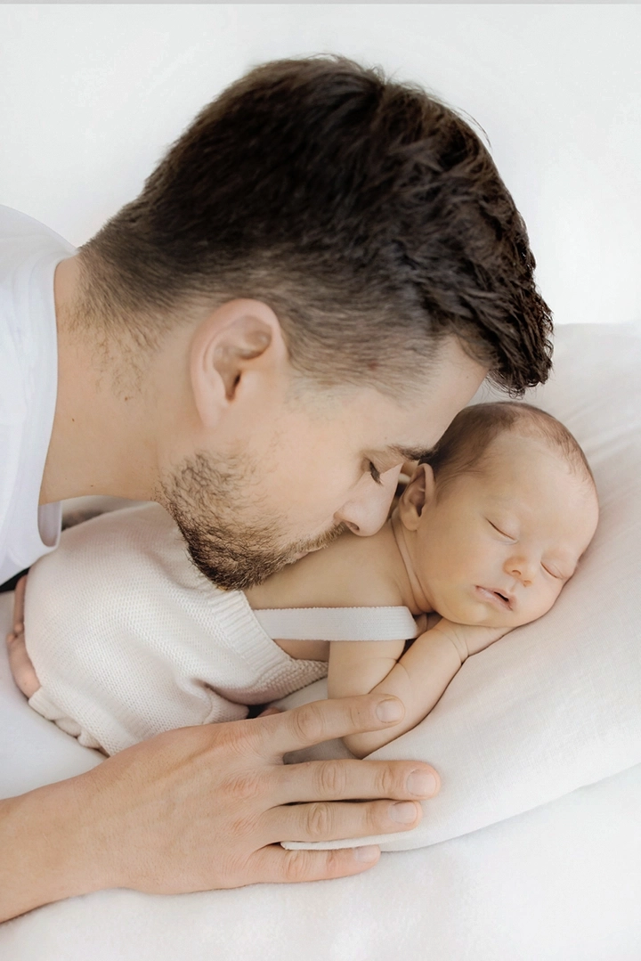 Photo de papa qui embrasse son bébé sur le dos